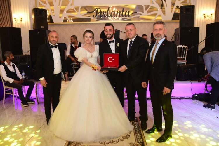 MHP İl Başkan Yardımcısı Cemal Ersoy ve MHP Kestel İlçe Başkanı Tarkan Toraman, gelinle damada düğün hediyesi olarak Türk bayrağı ile Kur-an'ı Kerim armağan etti.